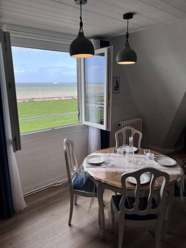 un comedor con una mesa con sillas y una ventana en L'air de la mer deux étoiles, en Dieppe