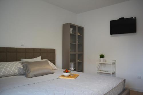 a bedroom with a bed with a television on the wall at Apartments Ćurić in Trogir