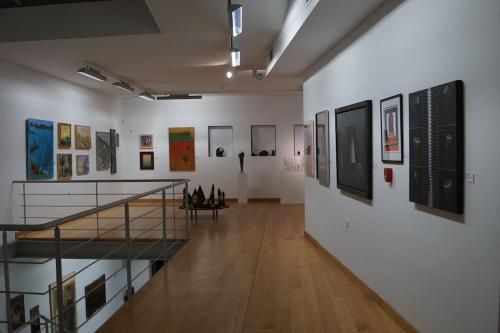 a museum gallery with paintings on the walls and a staircase at Mini Villas Blue in Keratokampos