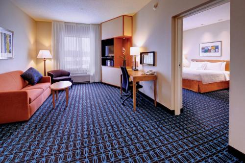 a hotel room with a bed and a couch and a desk at Fairfield Inn & Suites by Marriott Wausau in Weston