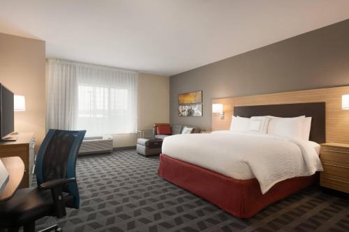 a hotel room with a large bed and a chair at TownePlace Suites by Marriott Dubuque Downtown in Dubuque