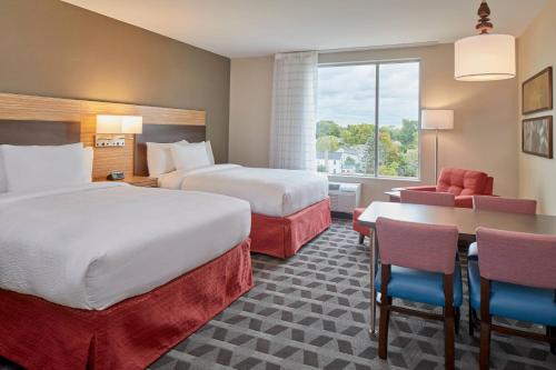 a hotel room with two beds and a table and chairs at TownePlace Suites by Marriott Columbus North - OSU in Columbus