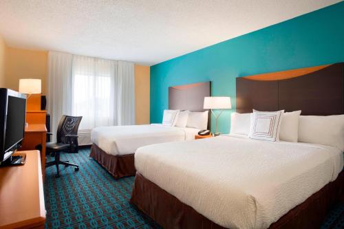 a hotel room with two beds and a flat screen tv at Fairfield Inn & Suites Fort Worth University Drive in Fort Worth