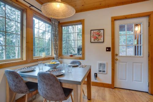 a dining room with a table and chairs and windows at Leavenworth Cabin with Private Hot Tub! in Leavenworth