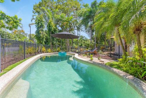 a swimming pool with an umbrella in a yard at Casa De Playa - Beach Townhouse in Holloways Beach