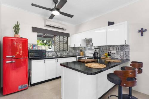 a kitchen with a red refrigerator and white cabinets at Casa De Playa - Beach Townhouse in Holloways Beach