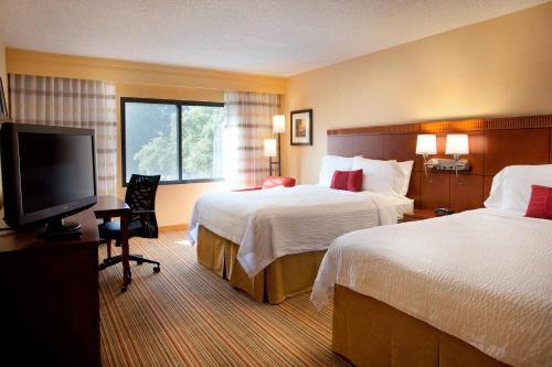 a hotel room with two beds and a flat screen tv at Courtyard Sacramento Airport Natomas in Sacramento