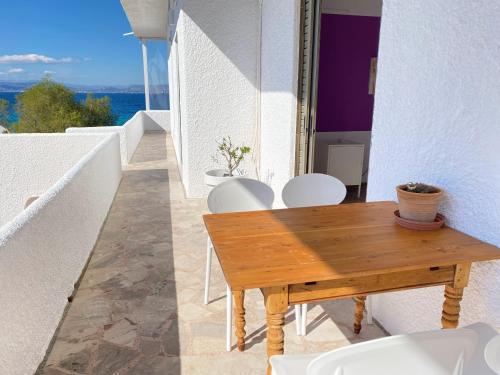 a balcony with a wooden table and white chairs at The Beachhouse Apartments in Vaia