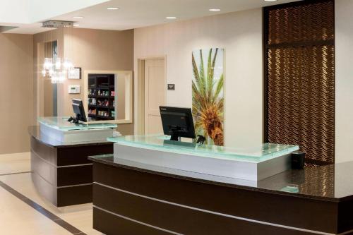 a lobby with a reception desk with a palm tree at Residence Inn by Marriott Fort Lauderdale Airport & Cruise Port in Dania Beach