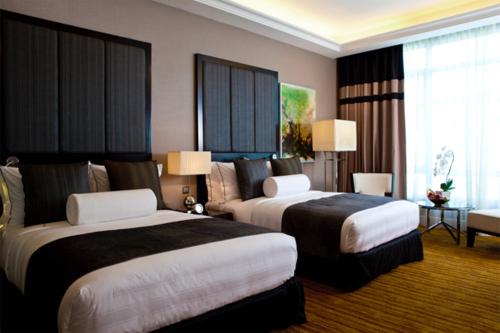 a hotel room with two beds and a couch at The Majestic Hotel Kuala Lumpur, Autograph Collection in Kuala Lumpur