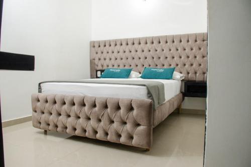 a bedroom with a large bed with a tufted headboard at Ayenda Hotel Muleke in Santa Marta