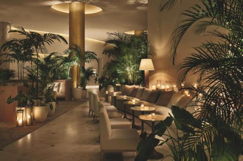 a waiting room with couches and tables and plants at The Miami Beach EDITION in Miami Beach