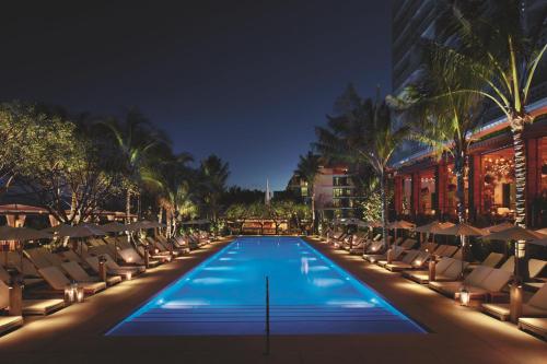 une piscine avec des chaises longues et un bâtiment dans l'établissement The Miami Beach EDITION, à Miami Beach