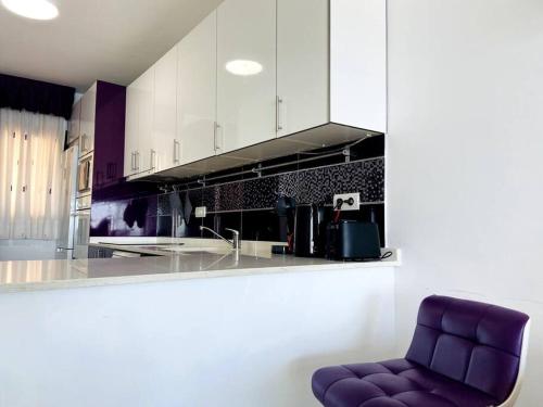una cucina con sedia viola di fronte a un bancone di Torrenueva Lux Seaview Apartment close to Marbella a La Cala de Mijas