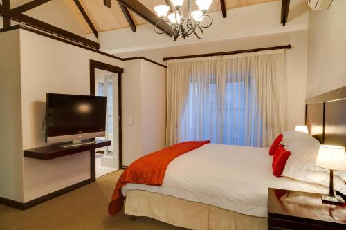 um quarto com uma cama grande e uma televisão de ecrã plano em Protea Hotel by Marriott Dorpshuis & Spa Stellenbosch em Stellenbosch