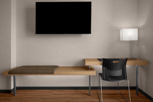 a desk with a chair and a television on a wall at AC Hotel by Marriott Vancouver Waterfront in Vancouver