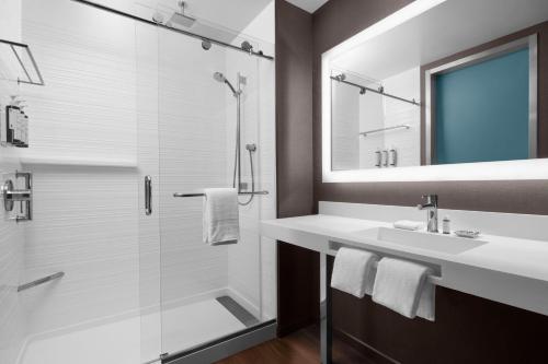 een badkamer met een douche, een wastafel en een spiegel bij AC Hotel by Marriott Vancouver Waterfront in Vancouver
