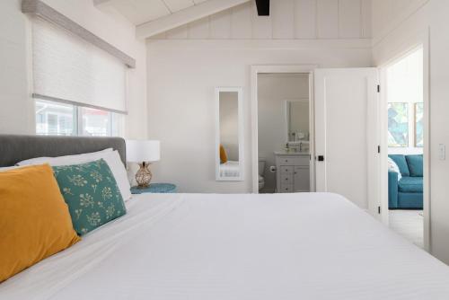 a white bedroom with a white bed with a yellow pillow at Pacific Villas in Oceanside