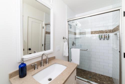 a white bathroom with a sink and a mirror at Pacific Villas in Oceanside