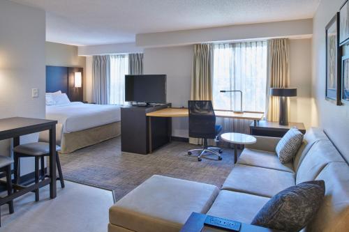 a hotel room with a couch and a bed and a desk at Residence Inn by Marriott Detroit / Novi in Novi