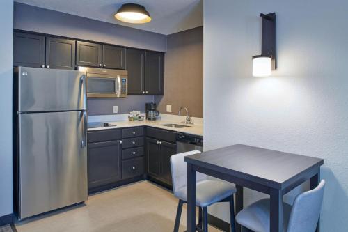 a kitchen with a stainless steel refrigerator and a table at Residence Inn by Marriott Detroit / Novi in Novi