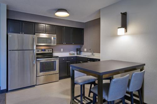 a kitchen with stainless steel appliances and a table with chairs at Residence Inn by Marriott Detroit / Novi in Novi