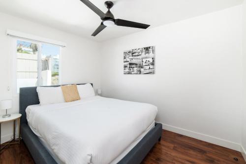 a bedroom with a white bed and a ceiling fan at Pacific Villas in Oceanside