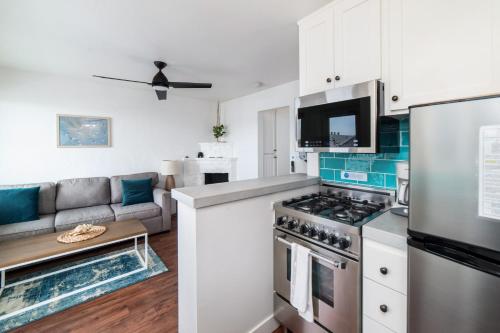 a kitchen with a stove top oven next to a couch at Pacific Villas in Oceanside