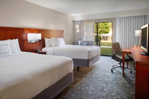 a hotel room with two beds and a desk at Courtyard by Marriott Fayetteville in Fayetteville