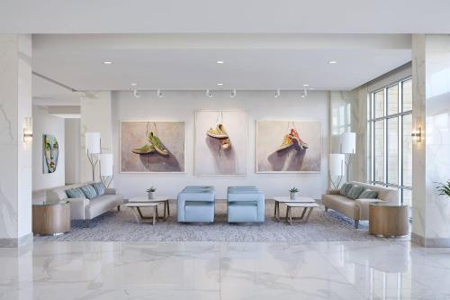 a lobby with paintings on the wall and couches and tables at HOTEL PASEO, Autograph Collection in Palm Desert