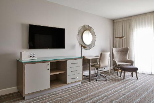 a hotel room with a desk with a television and chairs at HOTEL PASEO, Autograph Collection in Palm Desert