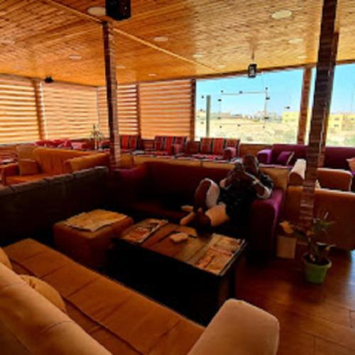 a person laying on a couch in a room with chairs at Petra cabin Roof top hostel in Wadi Musa