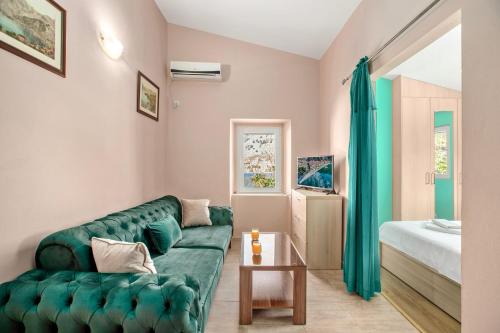 a living room with a green couch and a bed at Apartments Dončić in Kotor