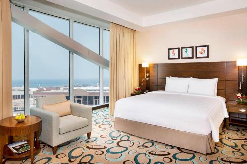 um quarto com uma cama, uma cadeira e janelas em Residence Inn by Marriott Jazan em Jazan