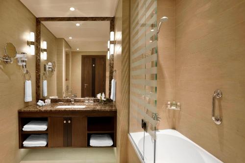 a bathroom with a tub and a sink and a mirror at Residence Inn by Marriott Jazan in Jazan