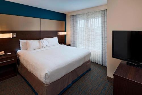 a hotel room with a bed and a flat screen tv at Residence Inn by Marriott Omaha West in Omaha