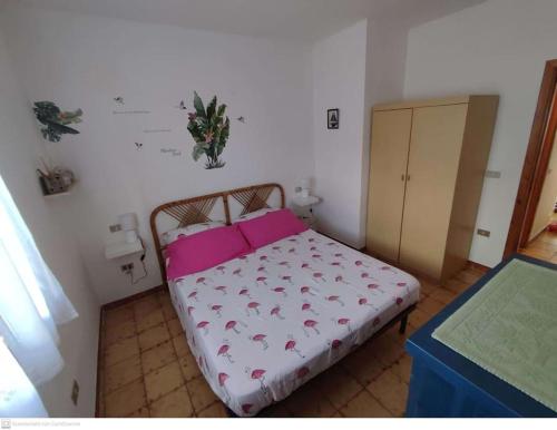Dormitorio pequeño con cama con almohadas rosas en Casa Flamingo House, en San Teodoro