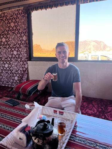 a man sitting in a room with a glass of wine at Raja camp in Wadi Rum