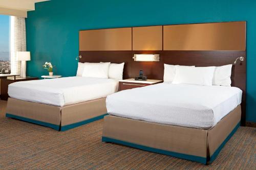 a hotel room with two beds and a blue wall at Residence Inn by Marriott Los Angeles LAX/Century Boulevard in Los Angeles