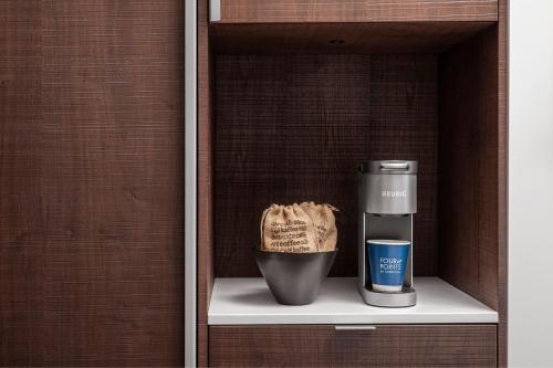 a shelf with a coffee maker and a cup on it at Four Points by Sheraton Flushing in Queens