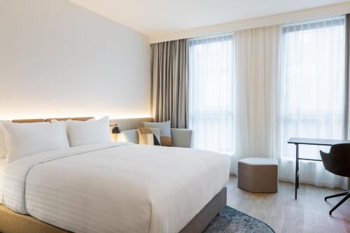 a hotel room with a large white bed and a desk at Residence Inn by Marriott Dortmund City in Dortmund