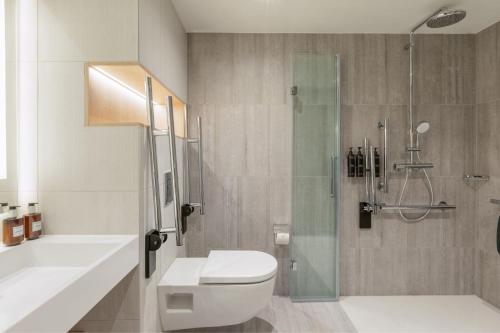 a bathroom with a shower and a toilet and a sink at Residence Inn by Marriott Dortmund City in Dortmund