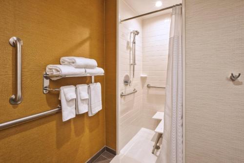 a bathroom with a shower and a toilet and towels at Fairfield Inn & Suites by Marriott Plattsburgh in Plattsburgh