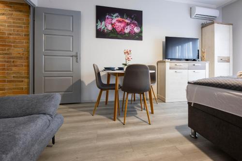 een kamer met een tafel en stoelen en een keuken bij Csipke Apartman in Makó