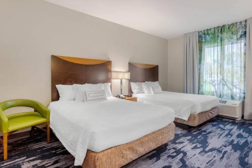 a hotel room with two beds and a yellow chair at Fairfield Inn & Suites by Marriott Houston Conroe in Conroe