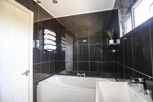 a black tiled bathroom with a tub and a sink at Alaw View in Amlwch