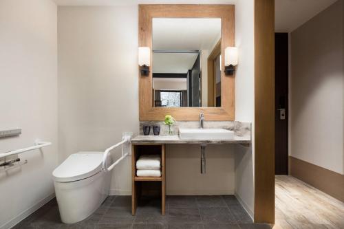 a bathroom with a toilet and a sink and a mirror at Courtyard by Marriott Hakuba in Hakuba