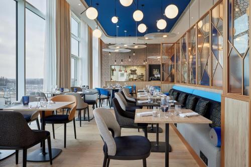 a restaurant with tables and chairs and windows at AC Hotel by Marriott Strasbourg in Strasbourg