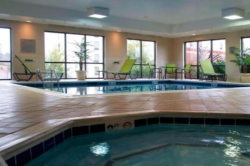 a pool in a hotel with chairs and tables at Courtyard by Marriott Hickory in Hickory