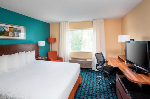 ein Hotelzimmer mit einem Bett und einem Flachbild-TV in der Unterkunft Fairfield Inn & Suites by Marriott Terre Haute in Terre Haute